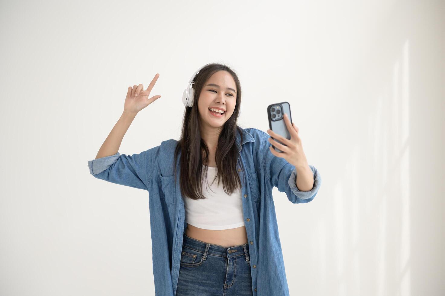 A young asian woman enjoying listening music and dancing over white background photo