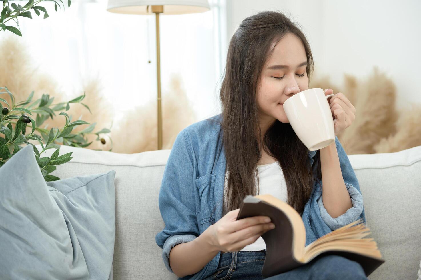 Young Asian woman enjoying reading book in living room at home photo