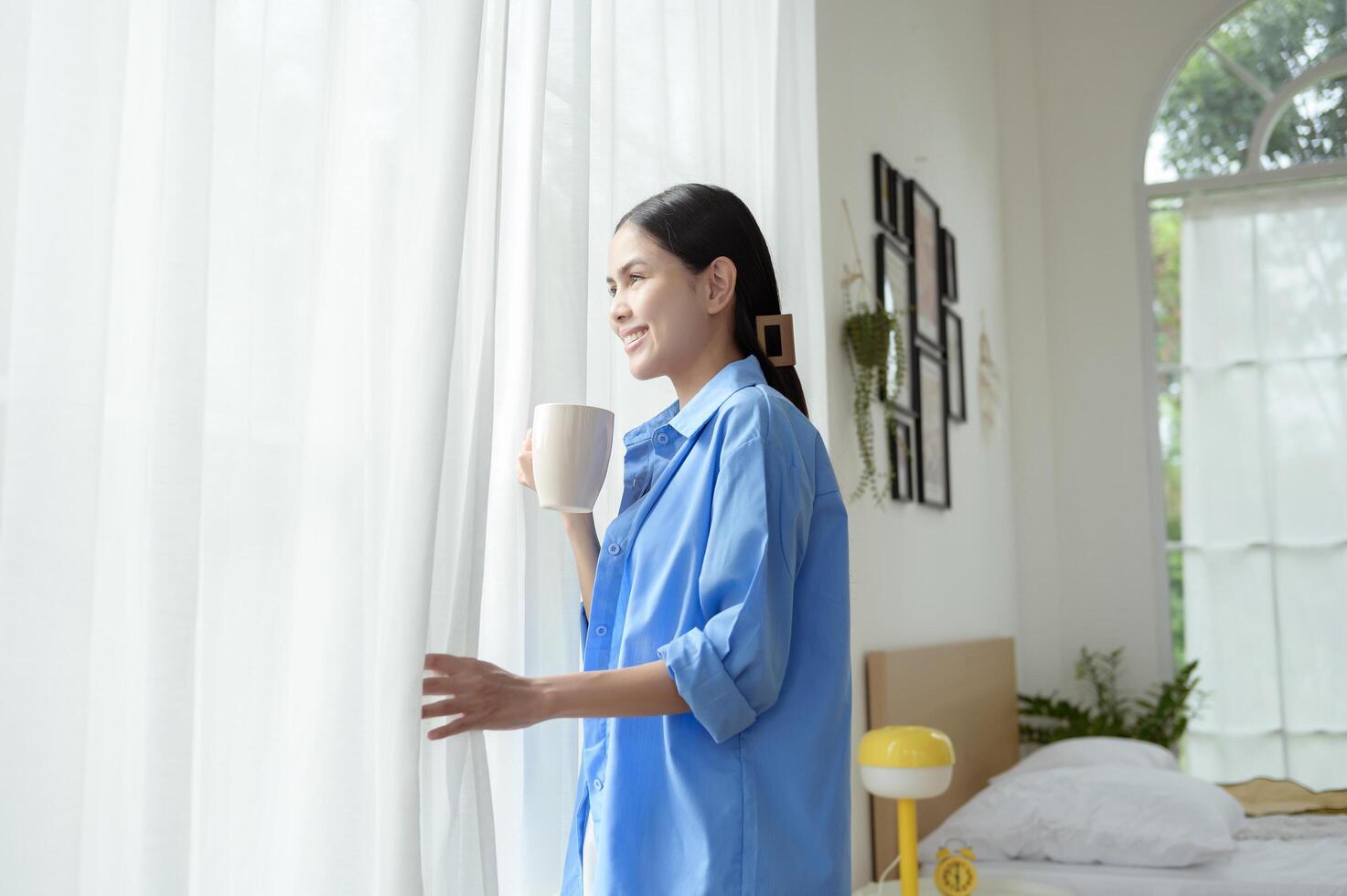 Morning Routine in a Bright Bedroom With a Woman Enjoying Coffee by the Window photo