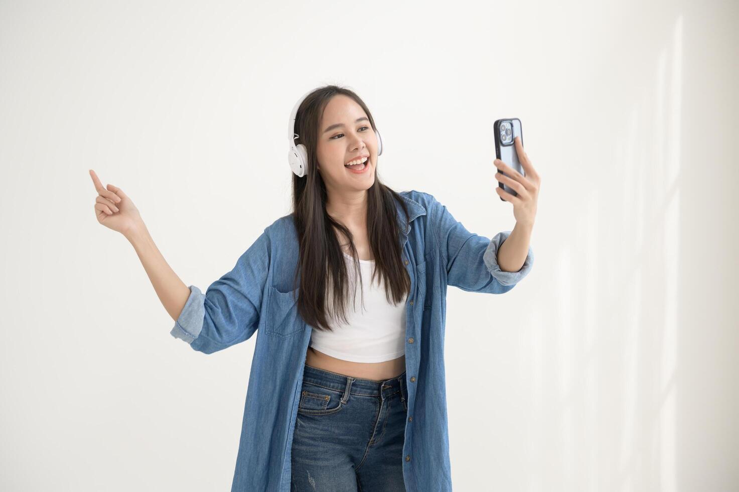 A young asian woman enjoying listening music and dancing over white background photo