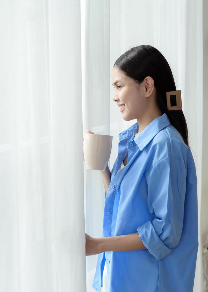 Morning Routine in a Bright Bedroom With a Woman Enjoying Coffee by the Window photo