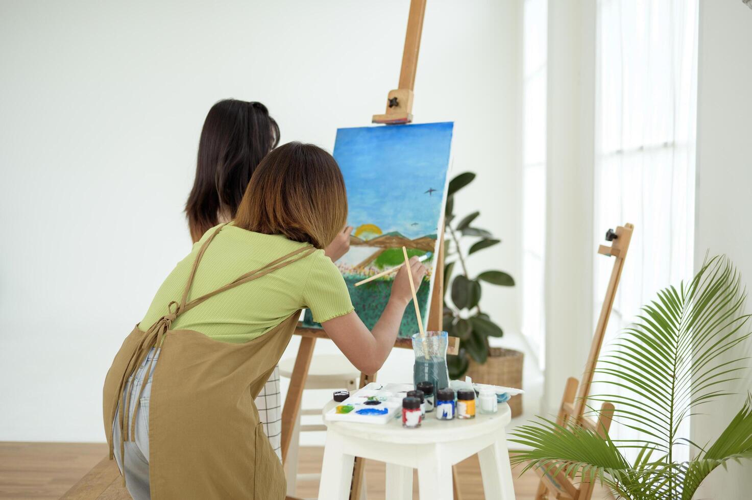 Two young Artists Creating Beautiful Landscape Paintings in a Bright Studio photo