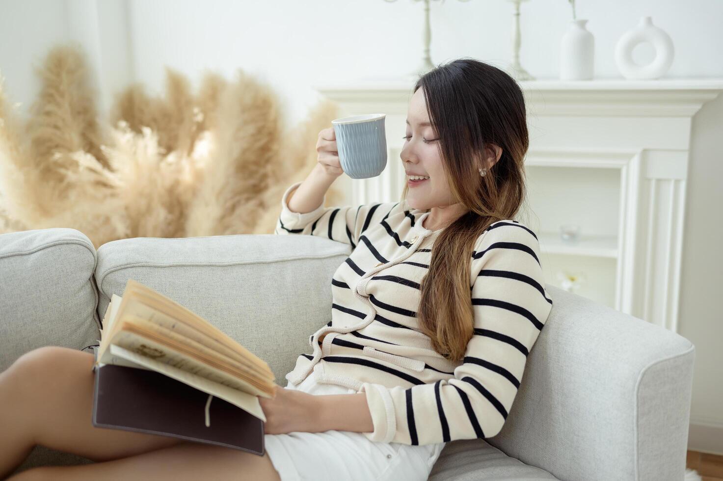 Young Asian woman enjoying reading book in living room at home photo
