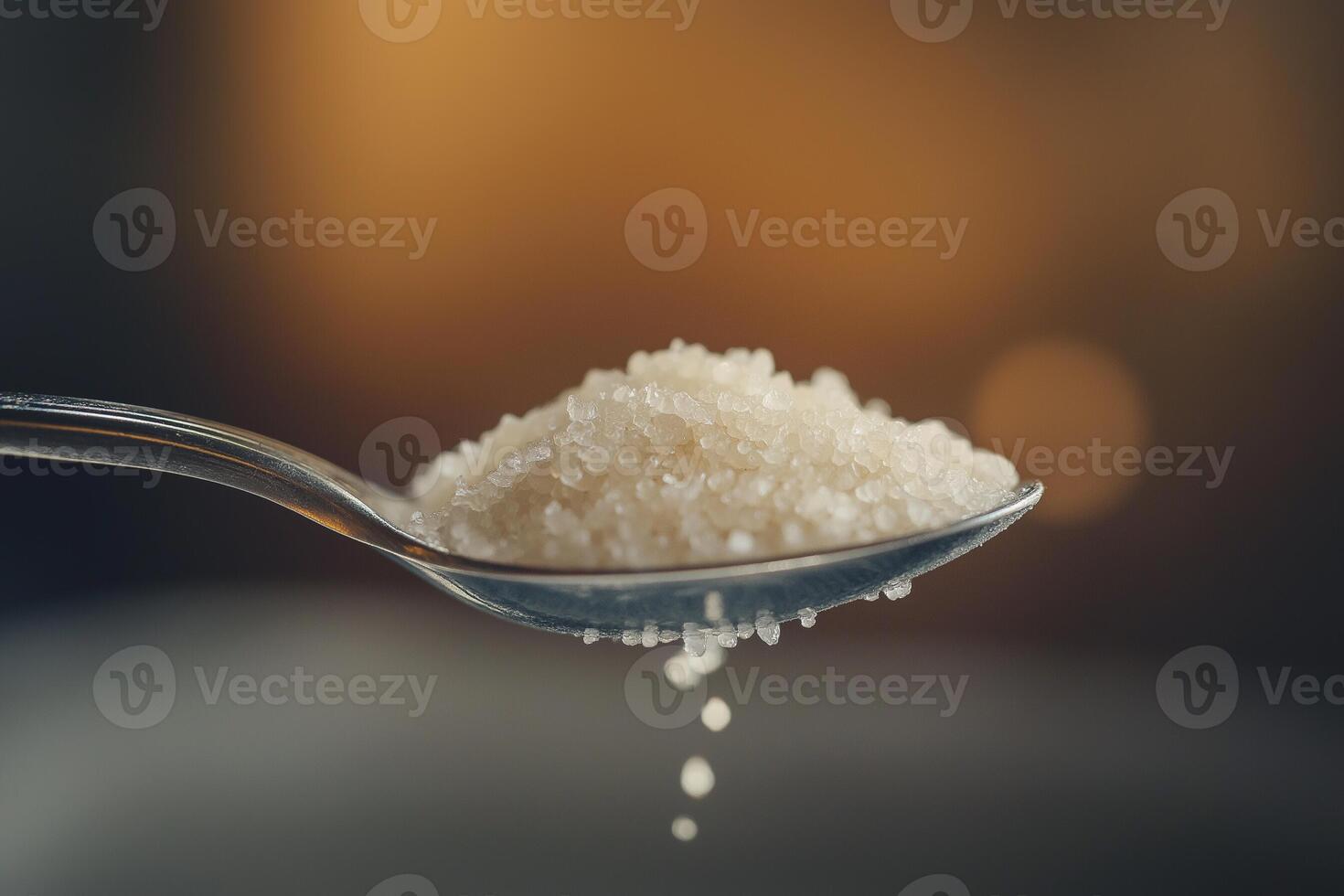 Teaspoon of white sugar with fine crystalline texture glistening under light photo