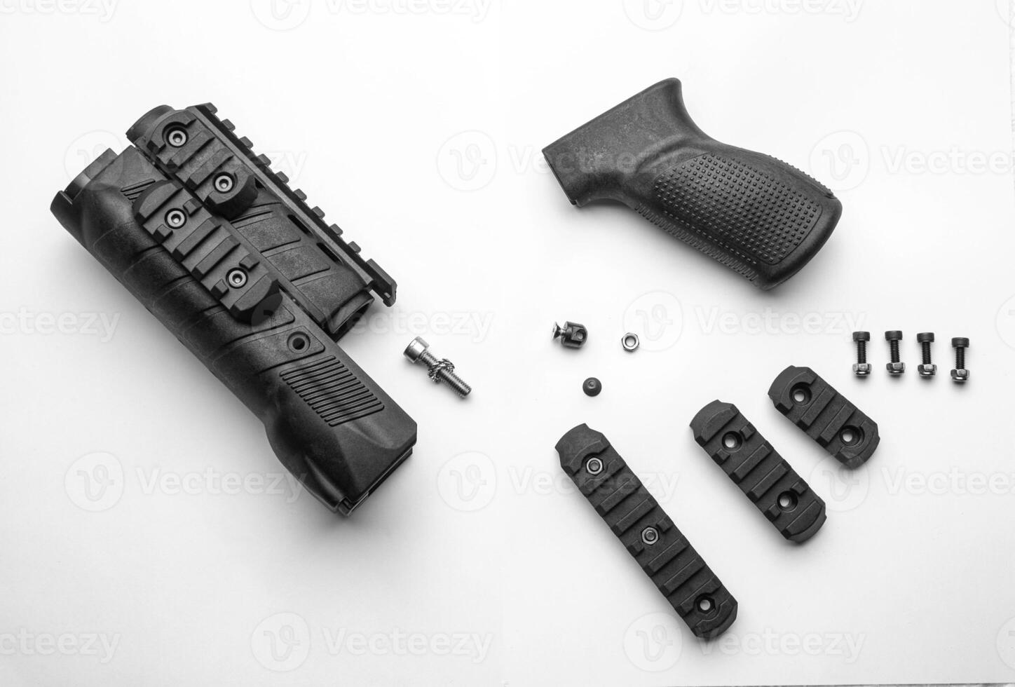 Parts of a firearm accessory, including a handguard, grip, screws, and rail sections, laid out on a white background photo