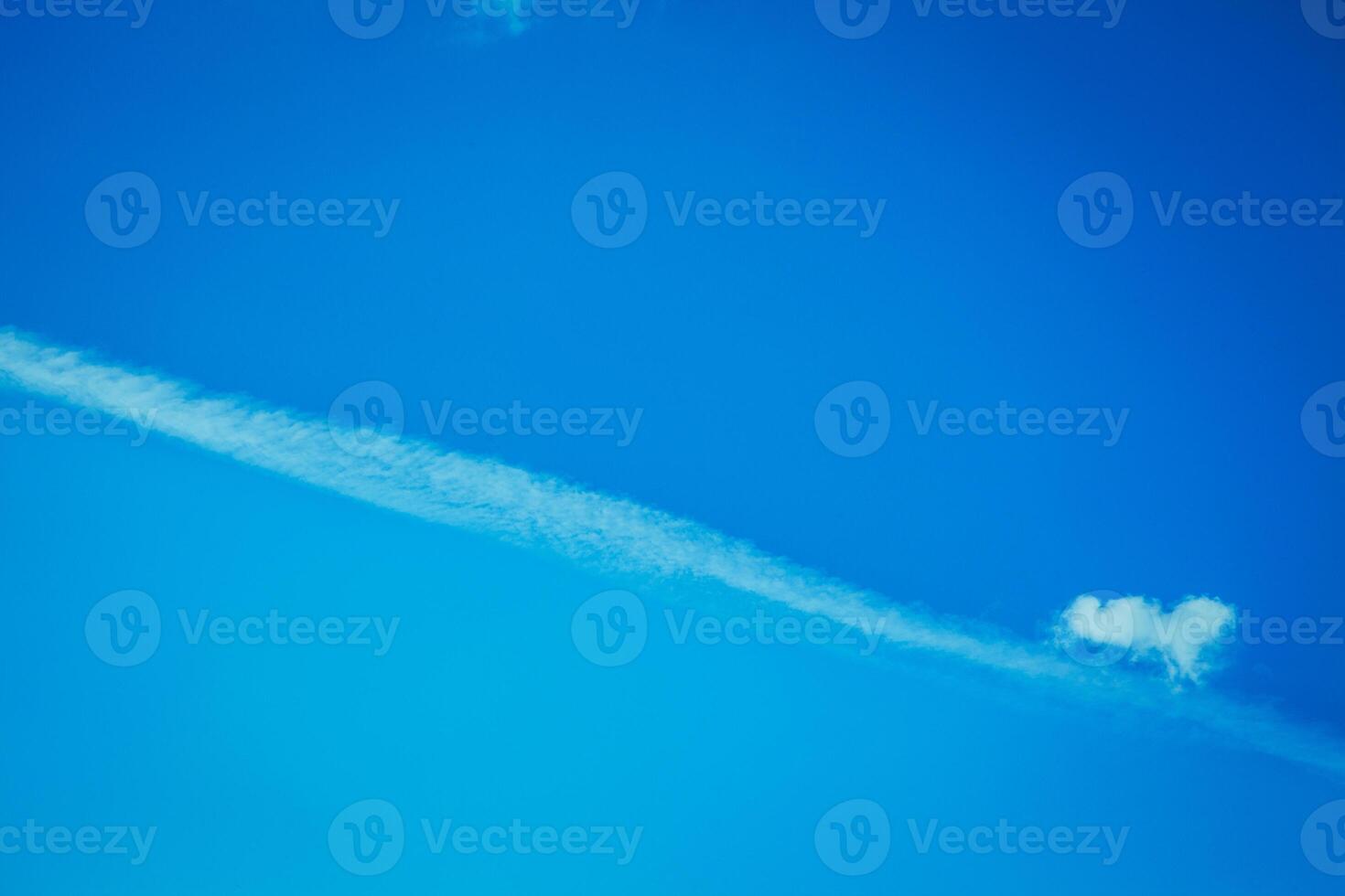 A single, thin cloud stretches across a bright blue sky photo
