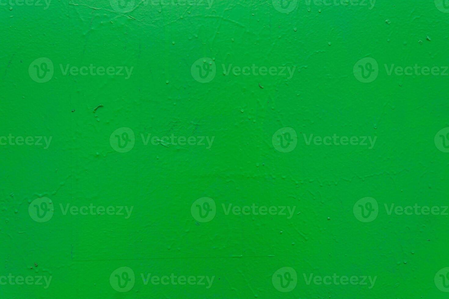 A textured green painted surface with subtle imperfections, rough texture, and small droplets. photo