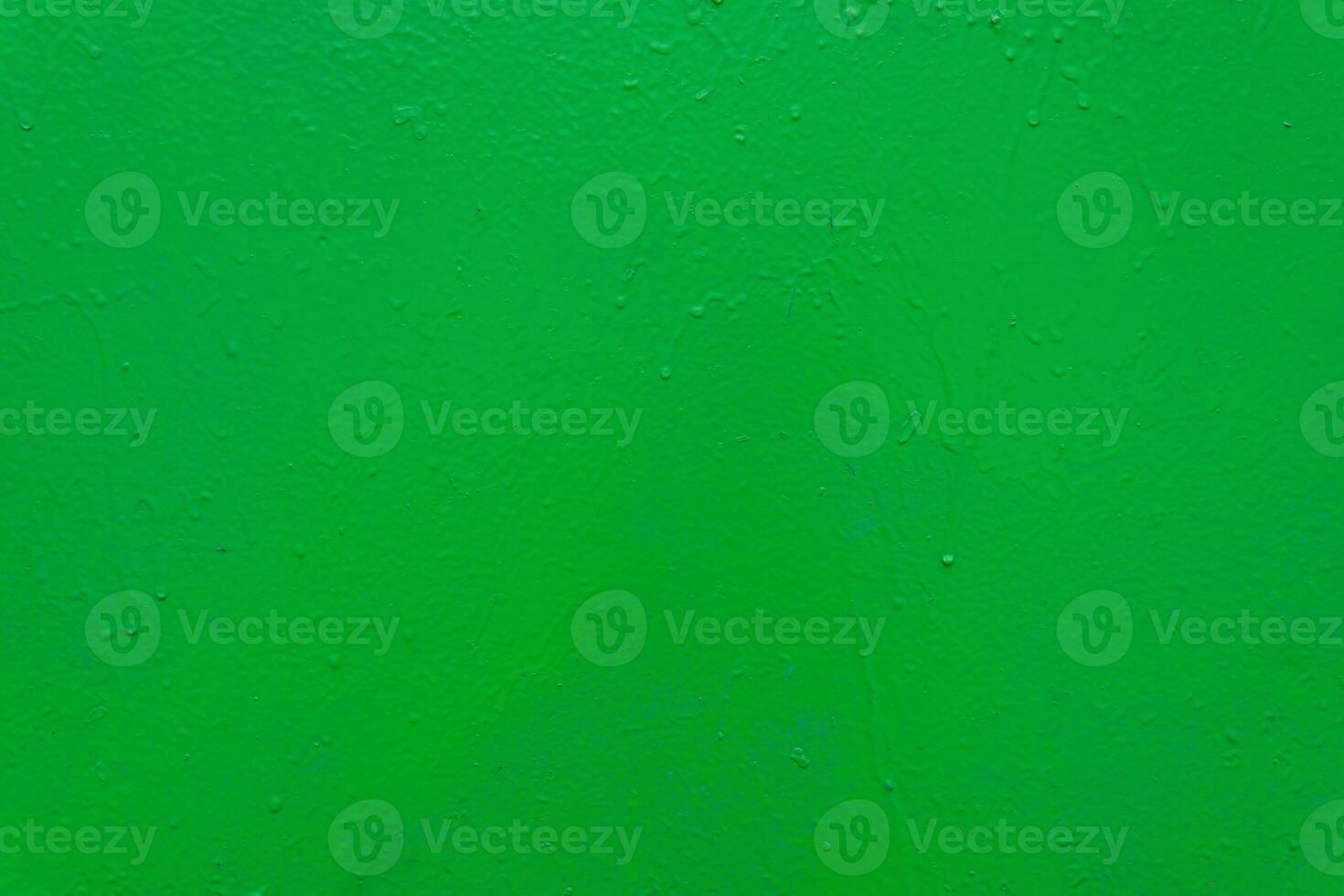 A textured green painted surface with subtle imperfections, rough texture, and small droplets. photo