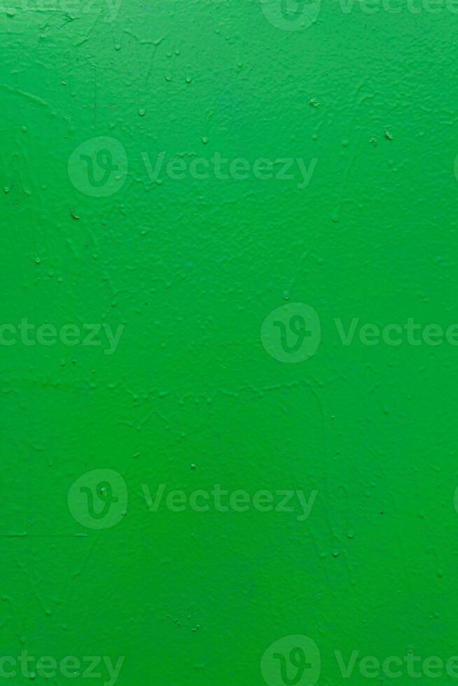 A textured green painted surface with subtle imperfections, rough texture, and small droplets. photo