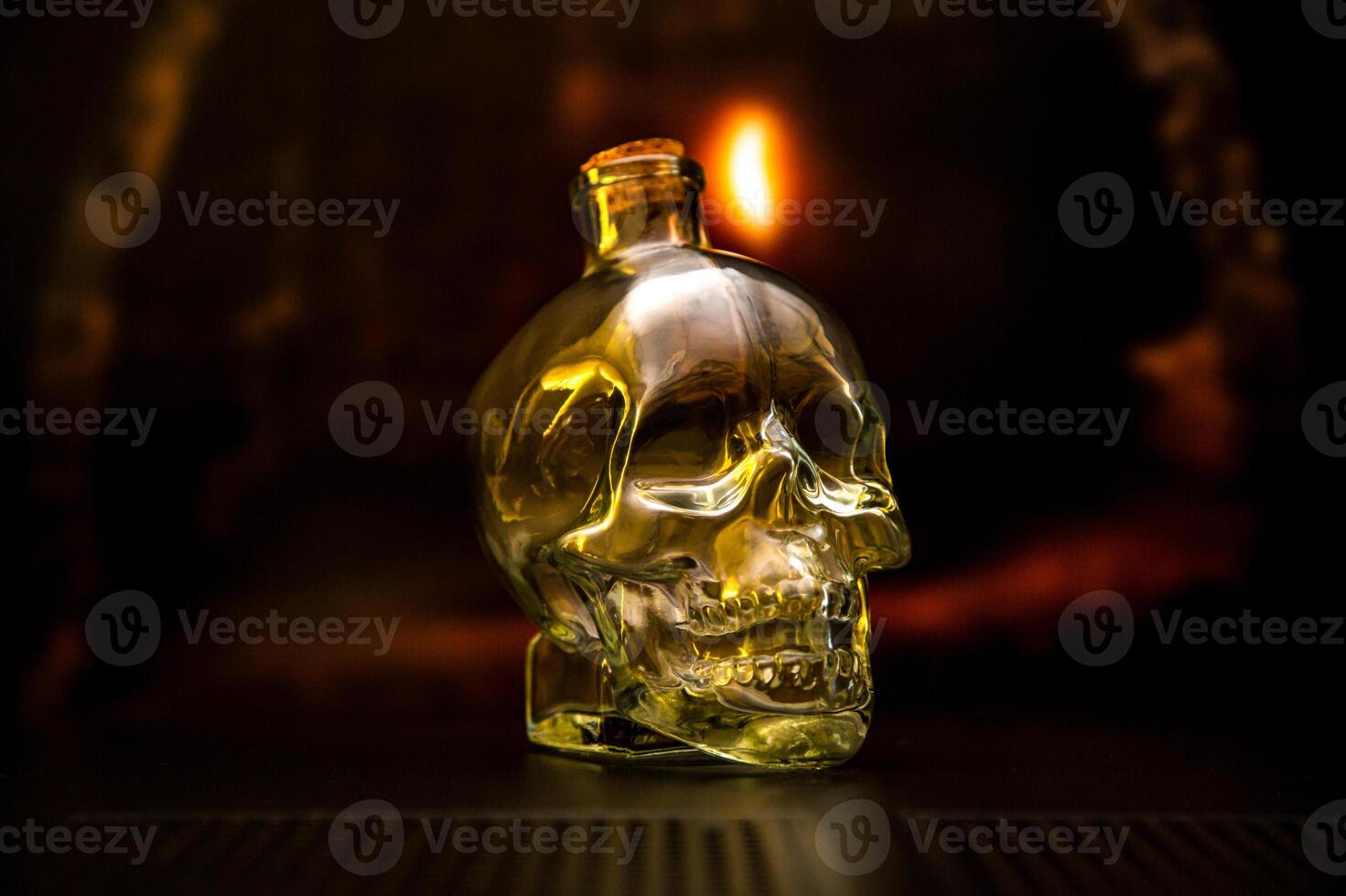 A glass bottle shaped like a human skull, illuminated with a warm, golden light. photo