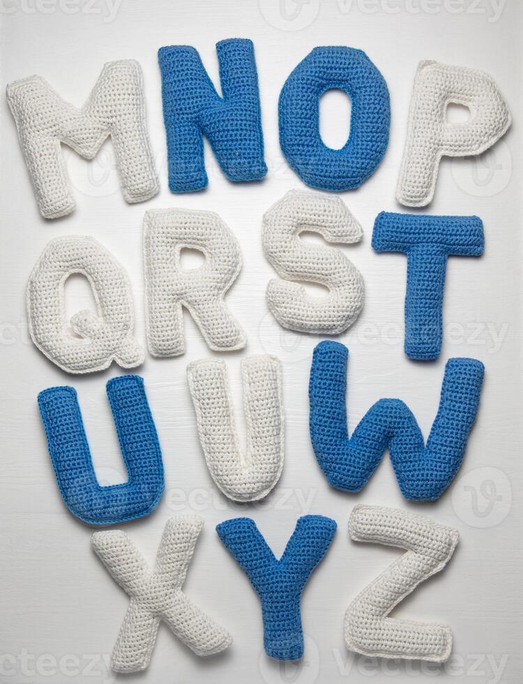 Handmade crocheted alphabet letters, blue and white, arranged on a white background, showcasing letters M to Z, perfect for educational materials. photo
