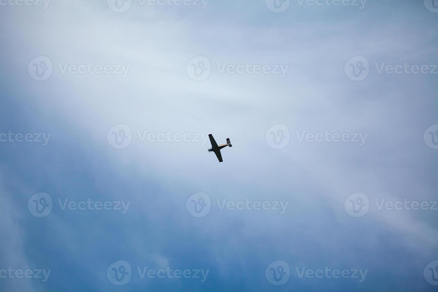 A small airplane flying against a backdrop of a clear blue sky with wispy clouds, creating a serene and open atmosphere photo