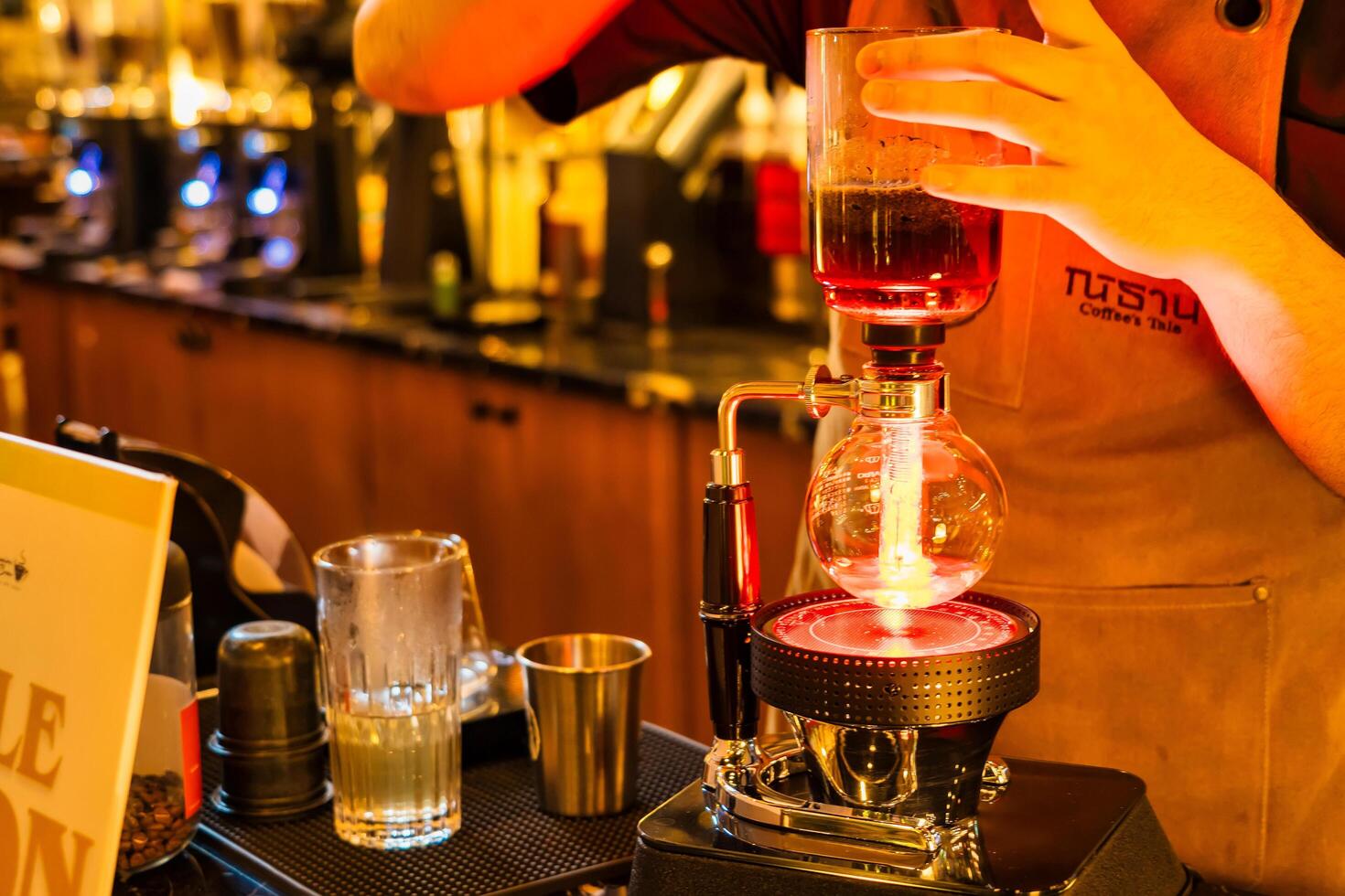 Chonburi, Thailand - November, 18, 2024.Expert Barista Preparing Syphon Coffee with a Vibrant Glow in a Coffee Shop Setting at Chonburi, Thailand. photo