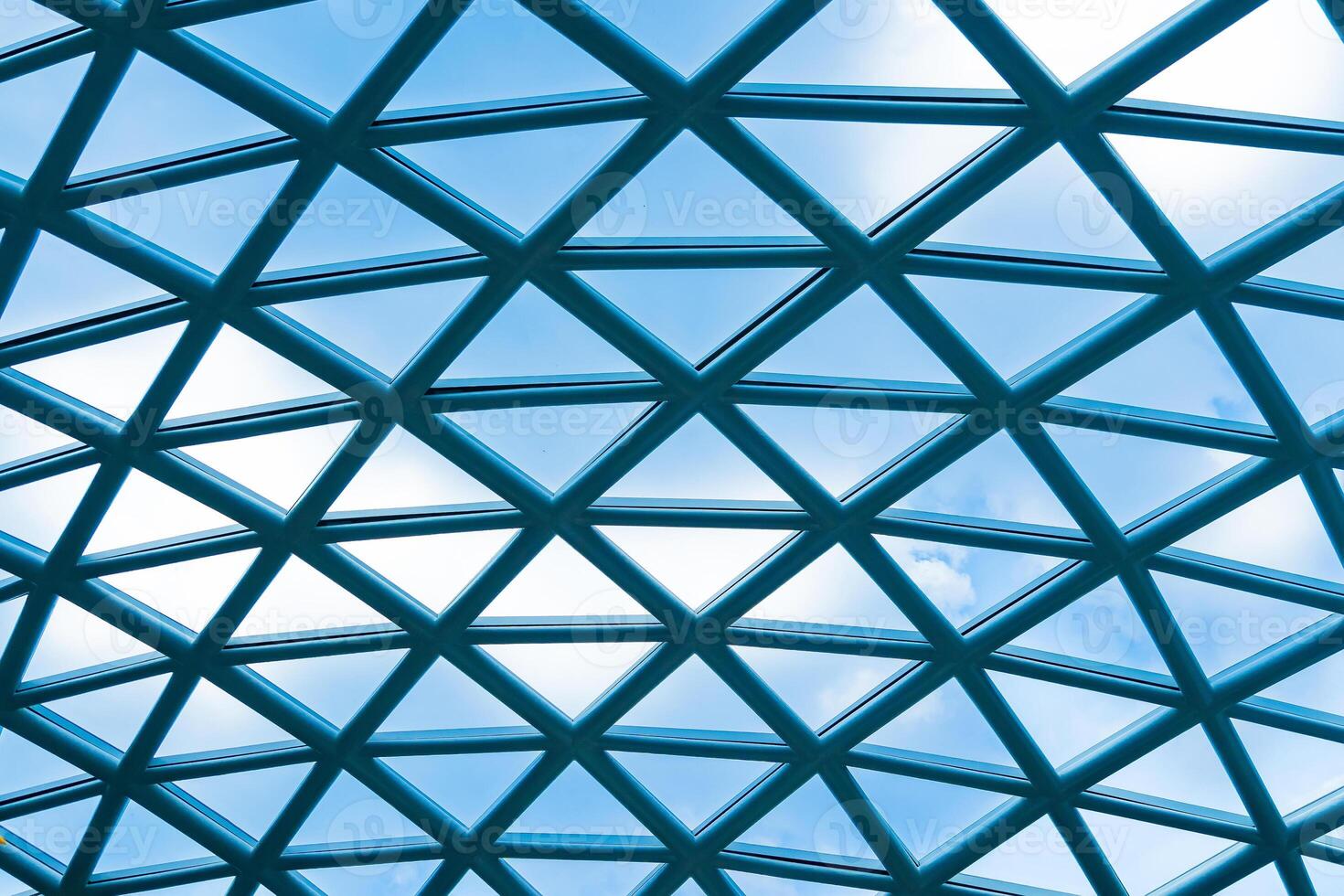 Abstract Architectural Pattern of a Geometric Glass Roof with Clear Blue Sky and White Clouds in the Background for Modern Urban Design Inspiration photo