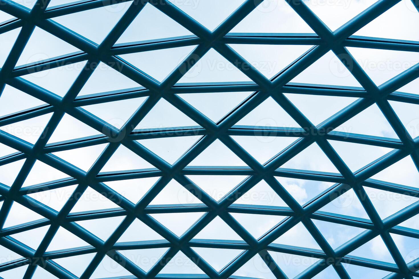Abstract Architectural Pattern of a Geometric Glass Roof with Clear Blue Sky and White Clouds in the Background for Modern Urban Design Inspiration photo