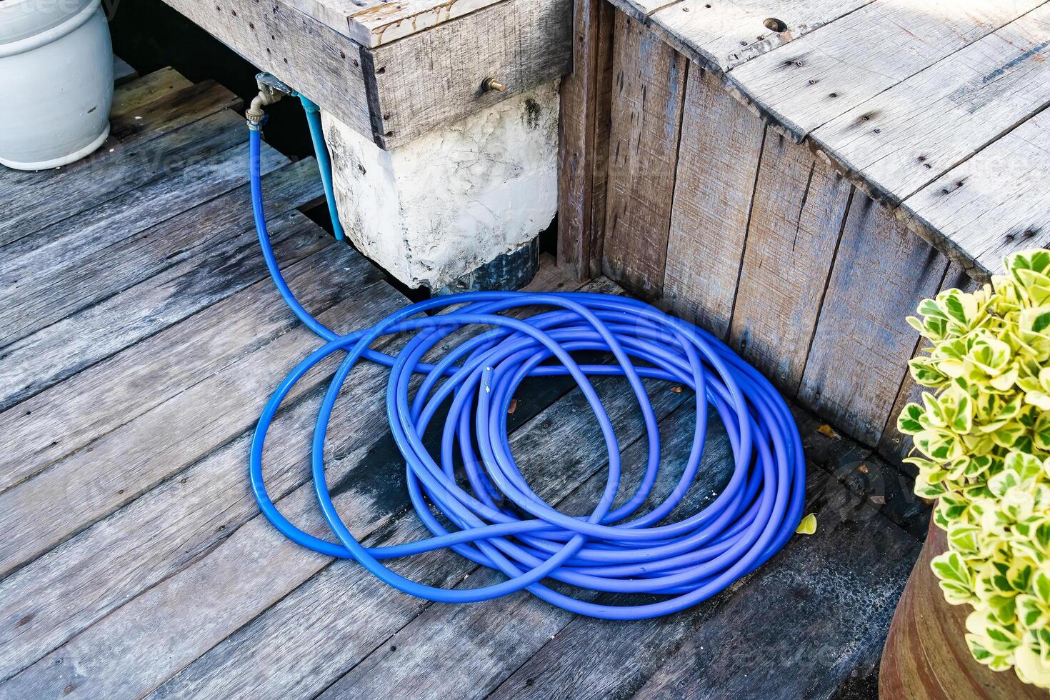 Outdoor Water Hose Neatly Coiled on Weathered Wooden Deck photo