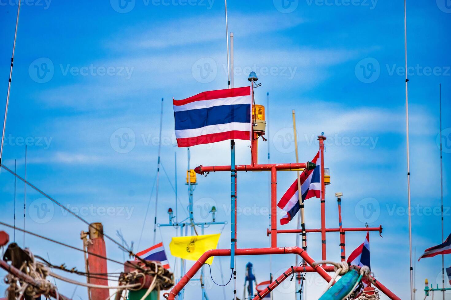 Colorful Thai Fishing Boats with National Flags Against a Clear Blue Sky photo