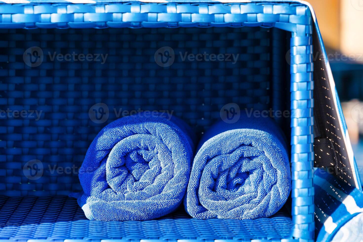 Vibrant Blue Towels Neatly Rolled on Wooden Shelf for Spa or Poolside Relaxation photo