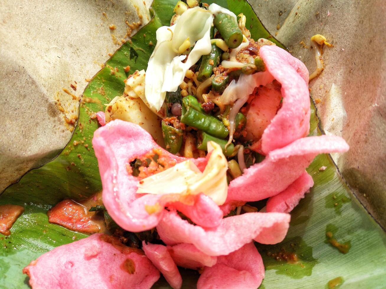 Close up view of Lotek, Indonesian traditional food made from boiled vegetable with peanut sauce served with crackers photo