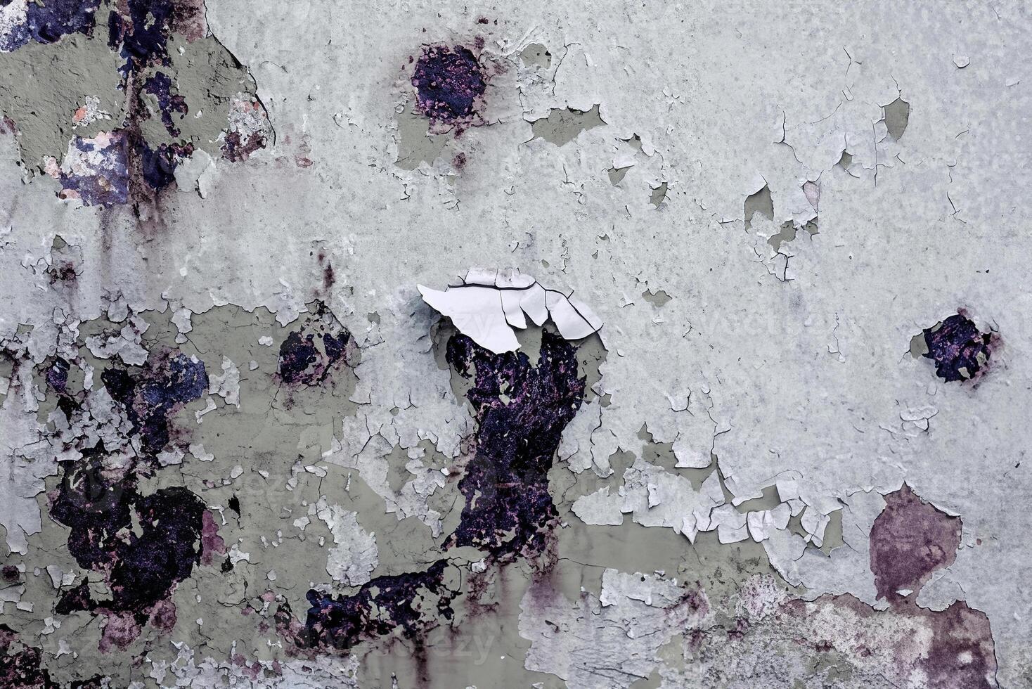 Close-up of peeling paint on a weathered surface with dark stains, ideal for grunge backgrounds and creative design. photo