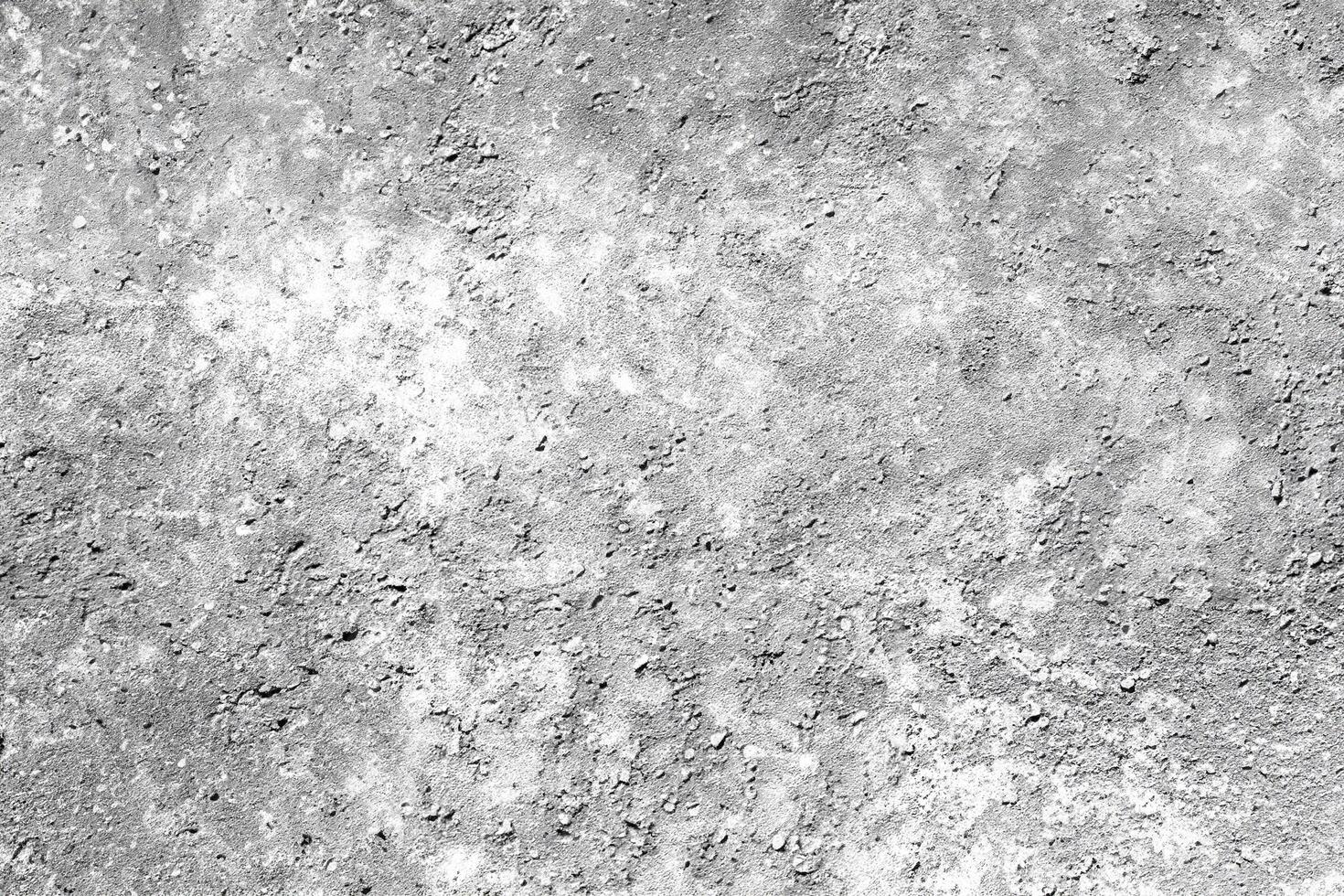 Close-up of a grainy, rough concrete texture with natural imperfections and weathered details in black and white. photo