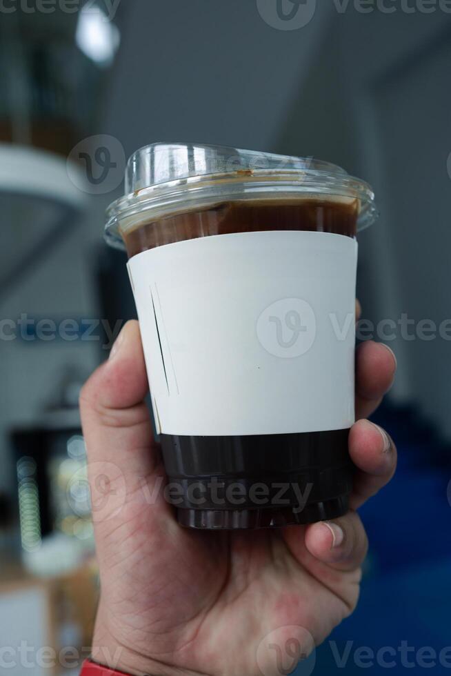 Holding ice coffee in plastic glass with white paper sleeve cup photo