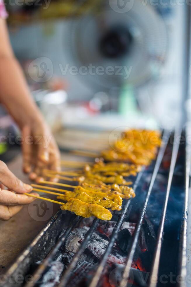 Someone is grilling pork satay on charcoal stove photo