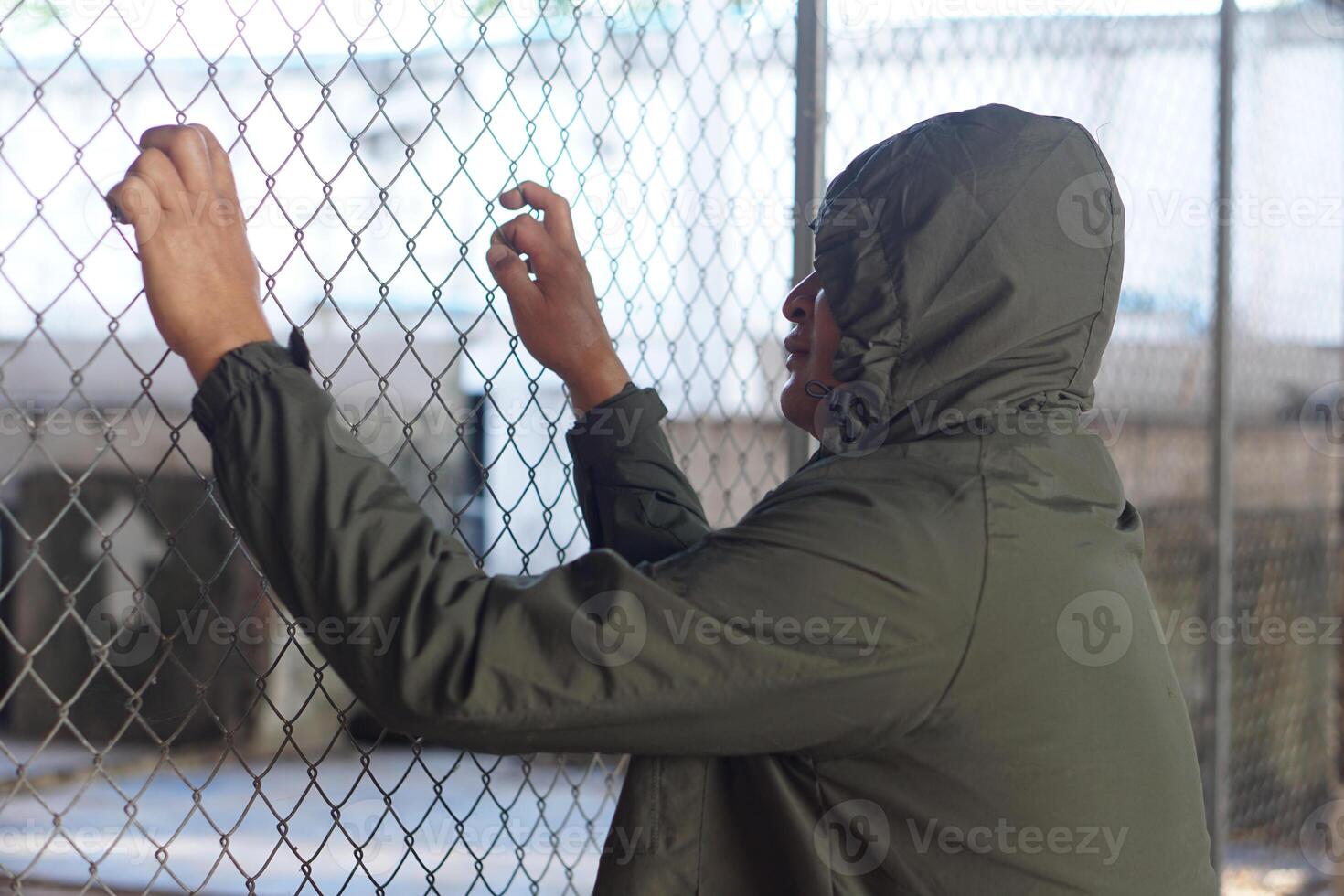 Man wears hoodie was detained in metal net cage . Concept, delinquency. Punishment. Detention. Criminals. Freedomless. Waiting for freedom. photo