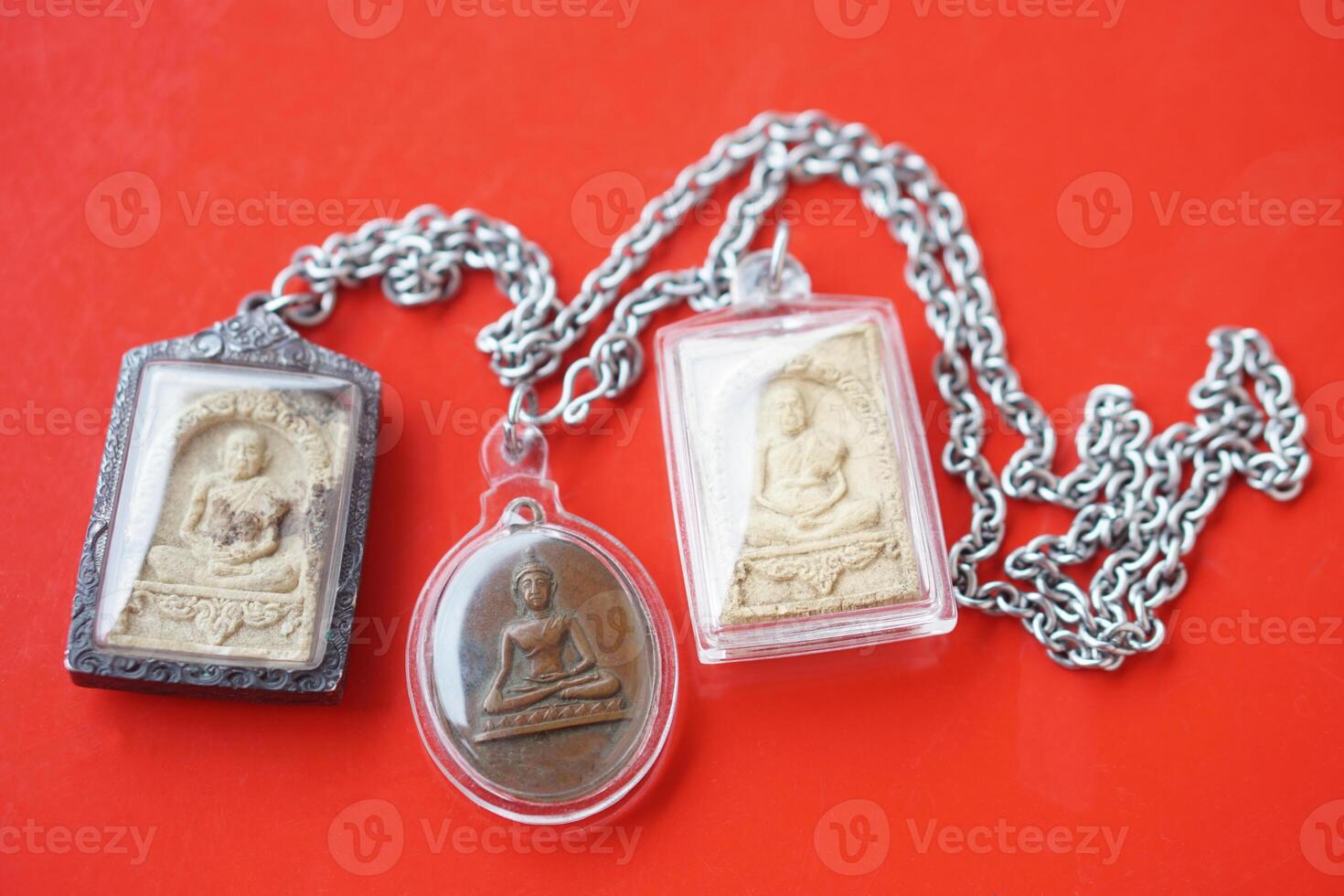 Thai Buddha amulets on red background. Concept, faith and belief of Buddhist for holy to protect from danger, bring good luck, business prosperity and wealth. Collecting amulet as hobbies or exchange. photo