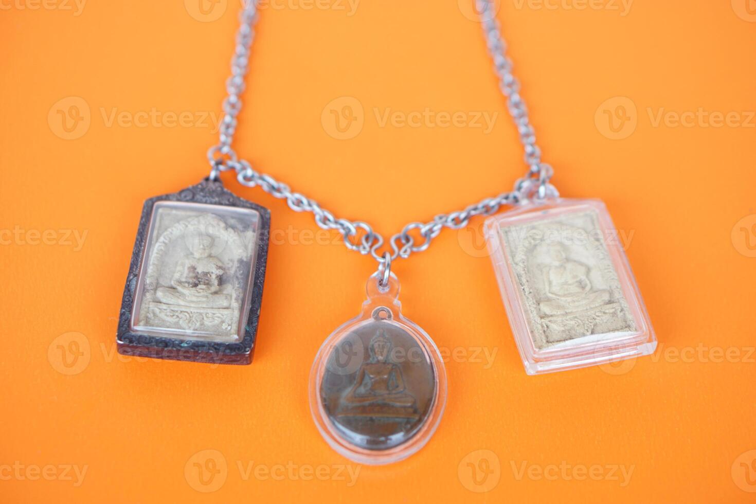 Buddha amulets on orange background. Concept, faith and belief of Buddhist for holy to protect from danger, bring good luck, business prosperity and wealth. Collecting amulet as hobbies or exchange. photo