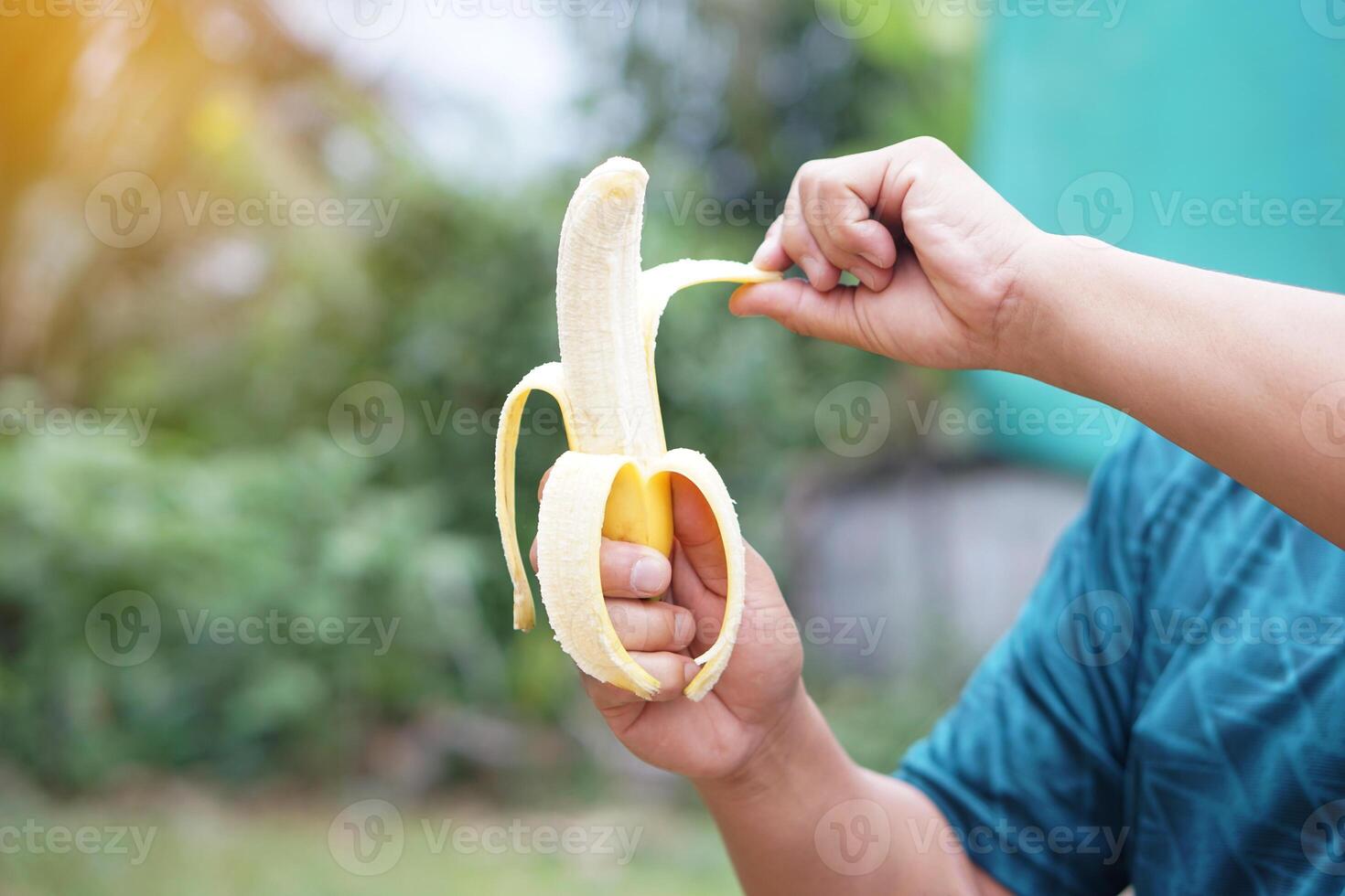 Close up hands are peeling banana to eat. Concept, nourishment and relieve hunger by eating banana, Benefit to health with food nutrition value. Healthy lifestyle. Enjoy eating fruits. photo