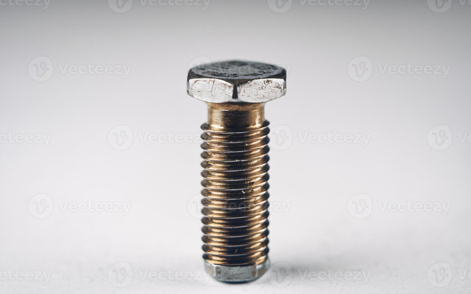 Close-up of a metallic bolt against a plain background, showcasing its detailed texture and structure. photo