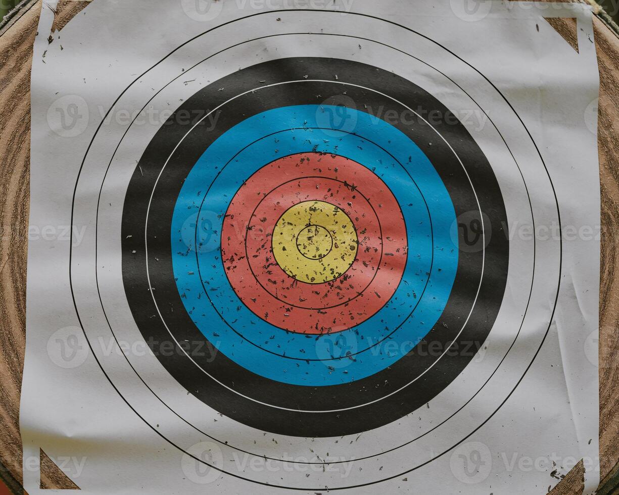 Close-up of a weathered archery target with colorful concentric circles, showcasing signs of use. photo