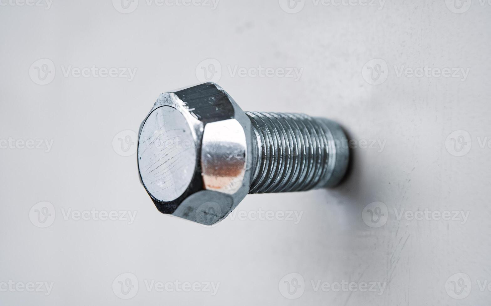 Close-up of a shiny steel bolt embedded in a light background, showcasing its texture and detail. photo