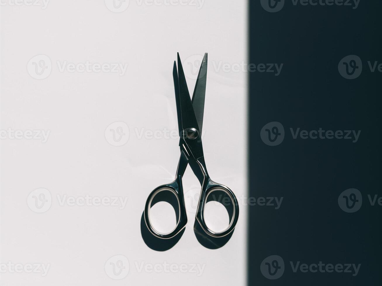 Close-up of stainless steel scissors casting a shadow on white paper. photo
