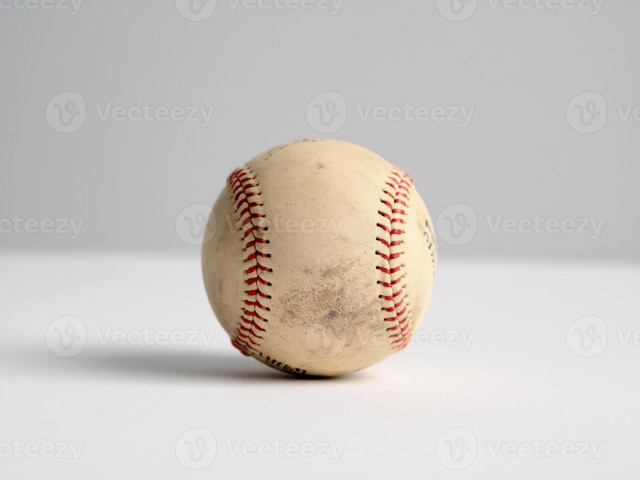 Close-up of a worn baseball with visible scuff marks and red stitching on a gray background. photo
