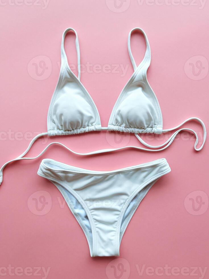 Stylish white bikini set laid out on pink backdrop, perfect for summer beach days. photo