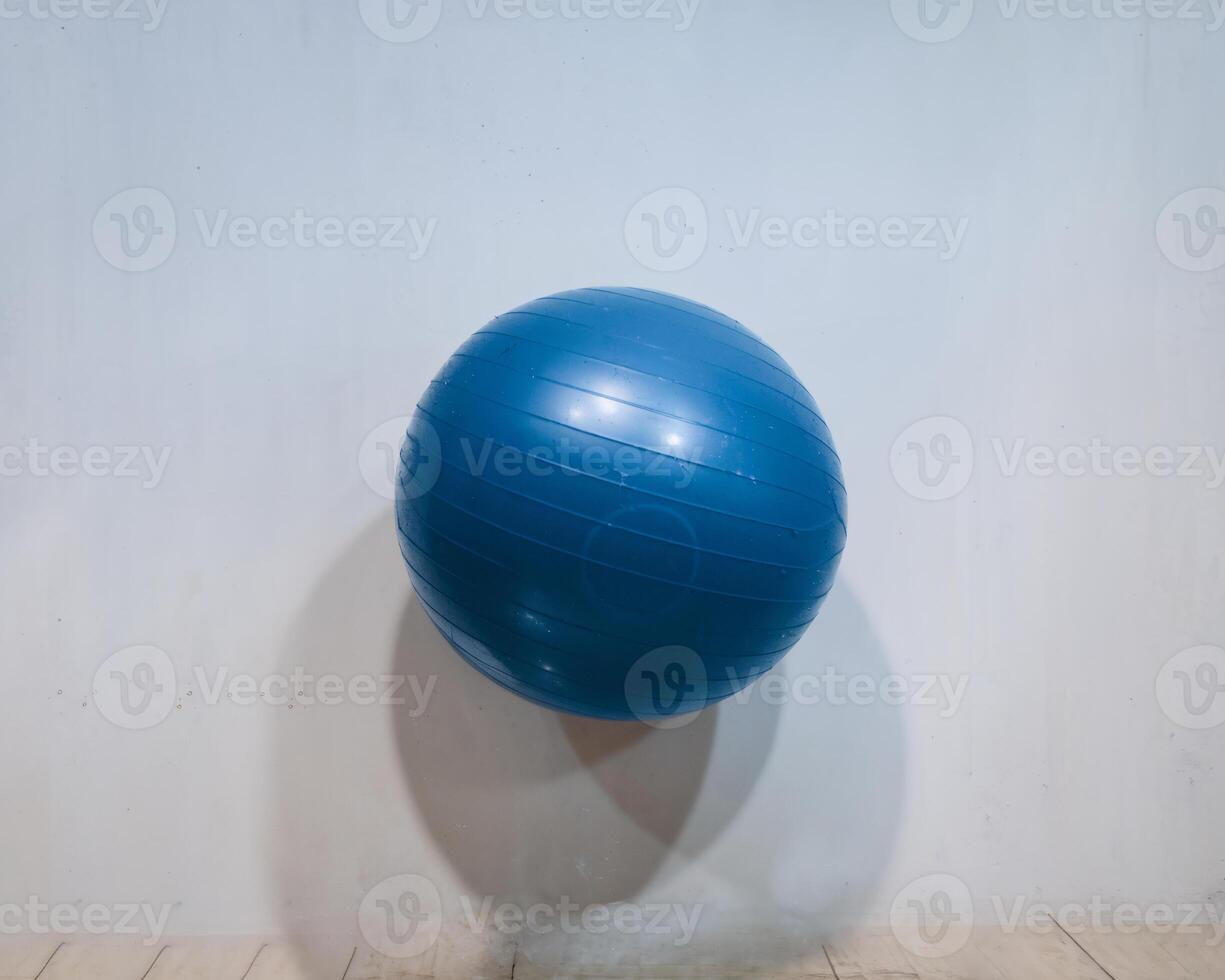 A blue exercise ball floating against a minimalist white wall, embodying fitness and tranquility. photo