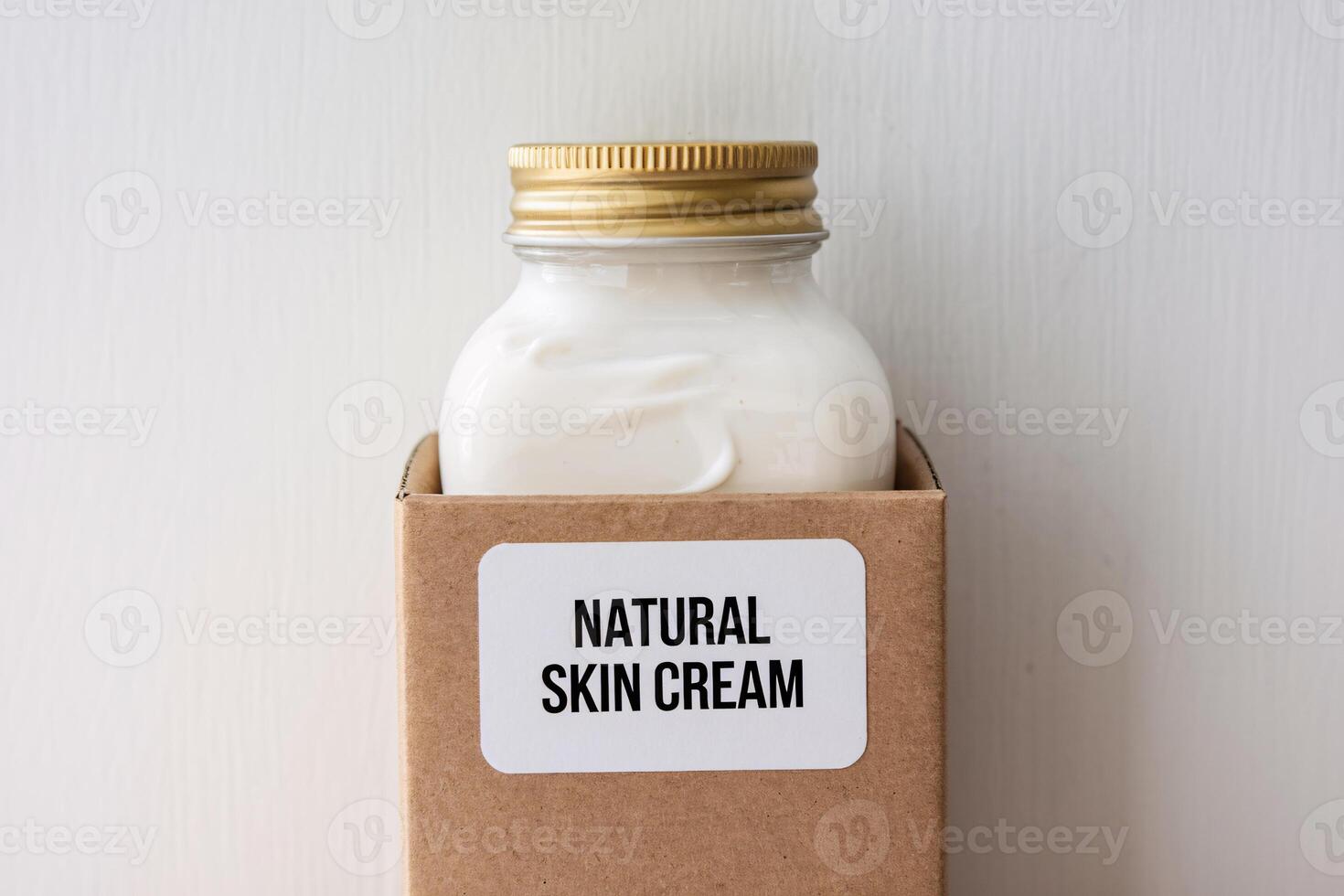 Natural skin cream in a glass jar with a gold lid, displayed in a cardboard box. photo