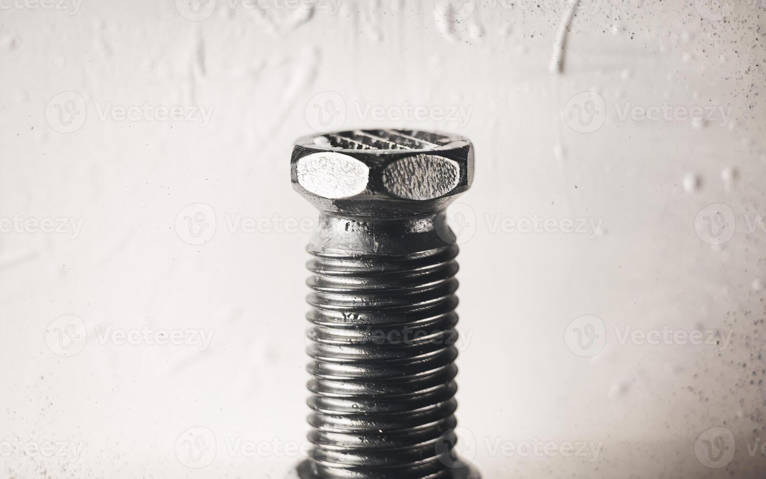 Close-up of a metallic bolt, showcasing its detailed threads and hexagonal head against a textured background. photo