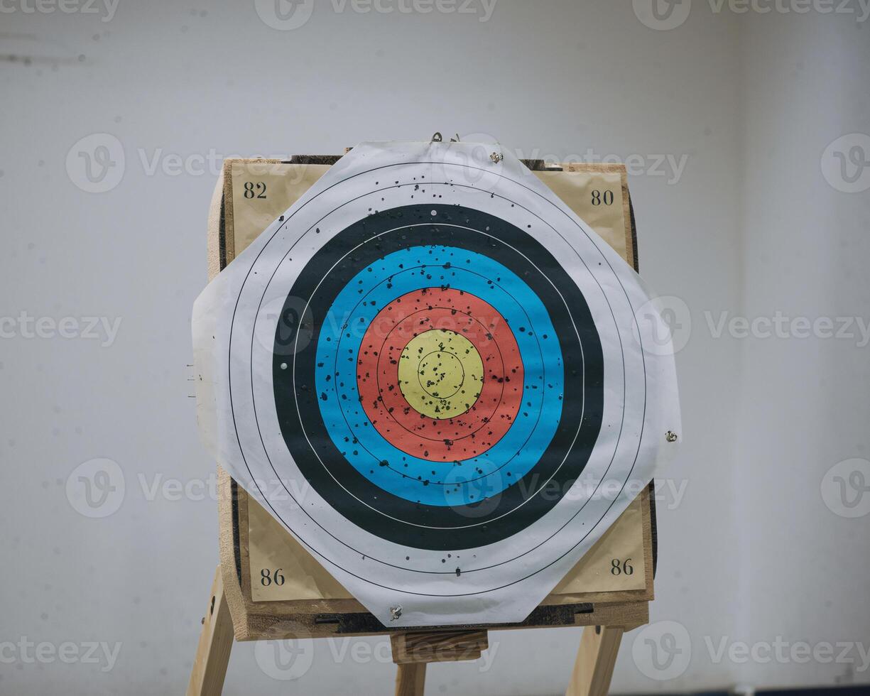 A close-up of a target board featuring colorful rings and numerous arrows puncturing the surface. photo