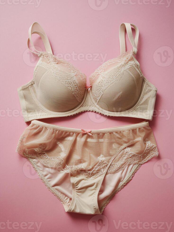 Elegant women's lingerie set in nude tones against a soft pink background, showcasing delicate lace details. photo
