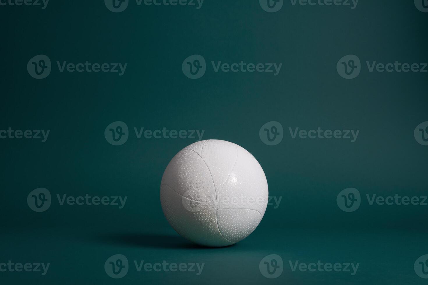 Minimalistic view of a white volleyball on a dark green background, highlighting its texture and shape. photo