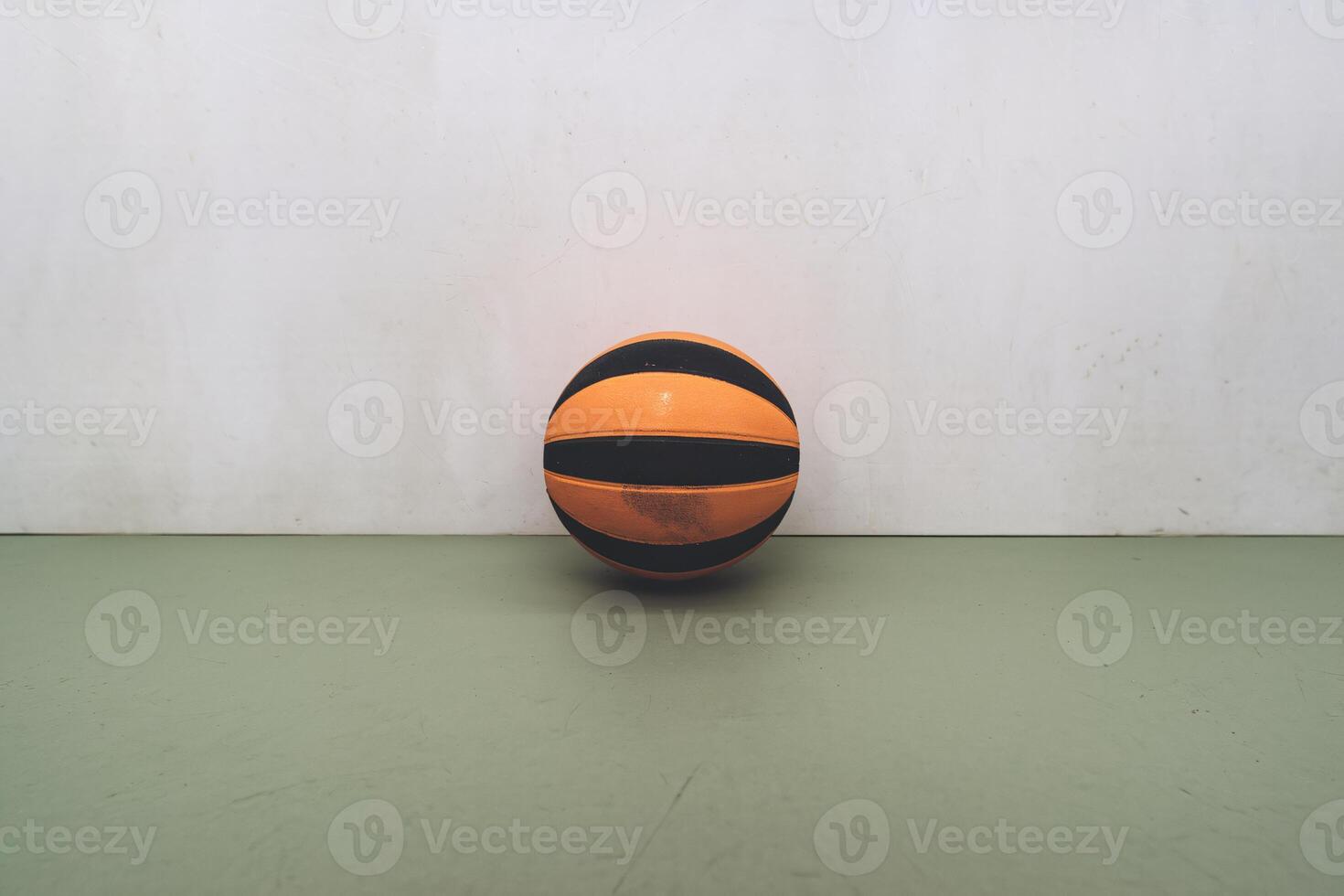 An orange and black basketball resting on a green surface against a plain background. photo
