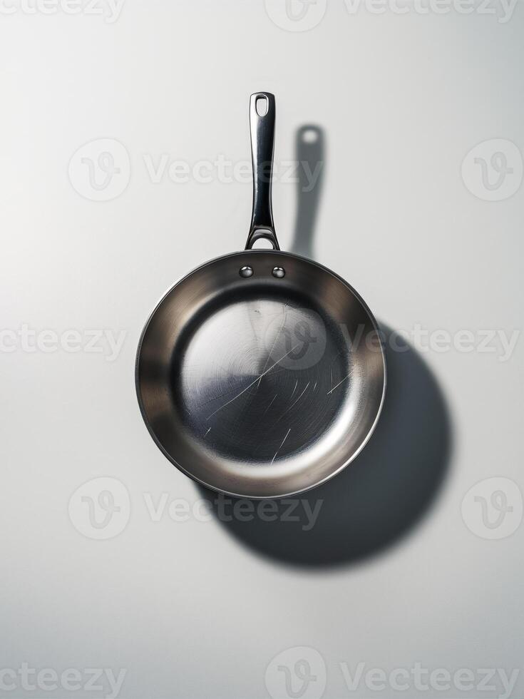 A reflective stainless steel frying pan cast in soft light, showcasing its sleek design and subtle scratches. photo