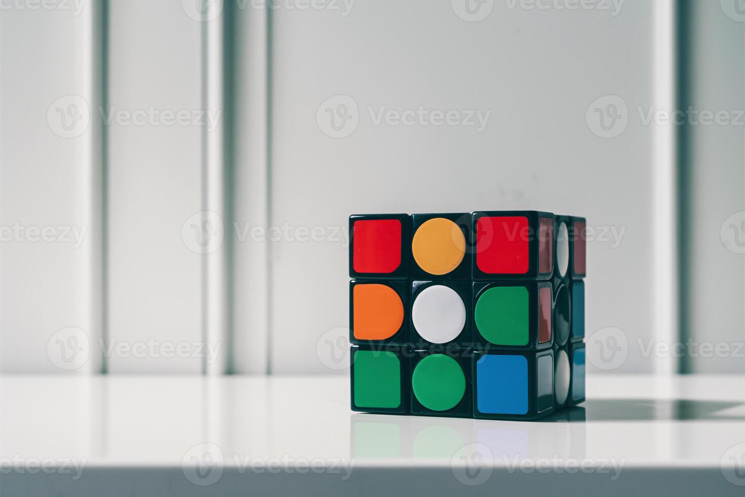 A colorful Rubik's Cube on a sleek white surface, showcasing its vibrant colors and geometric patterns. photo