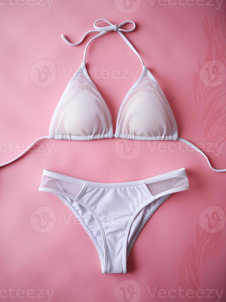 White bikini set arranged elegantly on a soft pink background, showcasing delicate design elements. photo