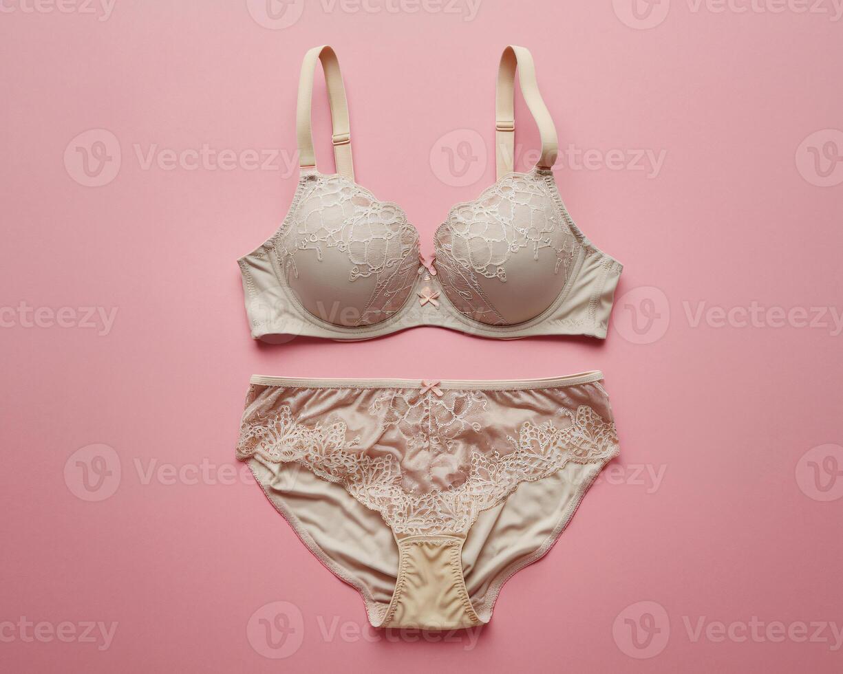 Elegant beige lace lingerie set laid out on a soft pink background, perfect for a feminine touch. photo