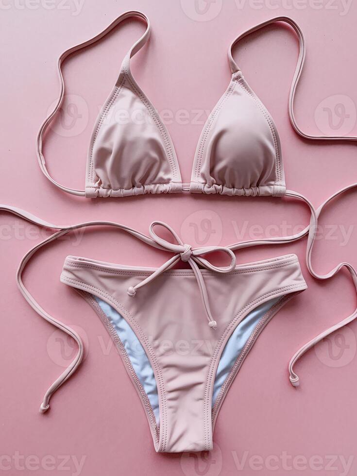 Stylish pink bikini set featuring a triangle top and adjustable tie bottoms on a soft pink backdrop. photo