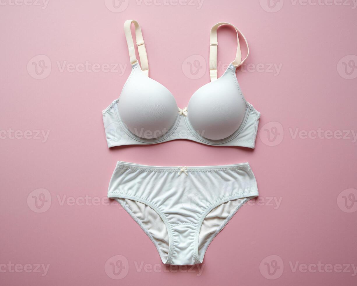Elegant white bra and panty set displayed on a soft pink background, showcasing a minimalist design. photo